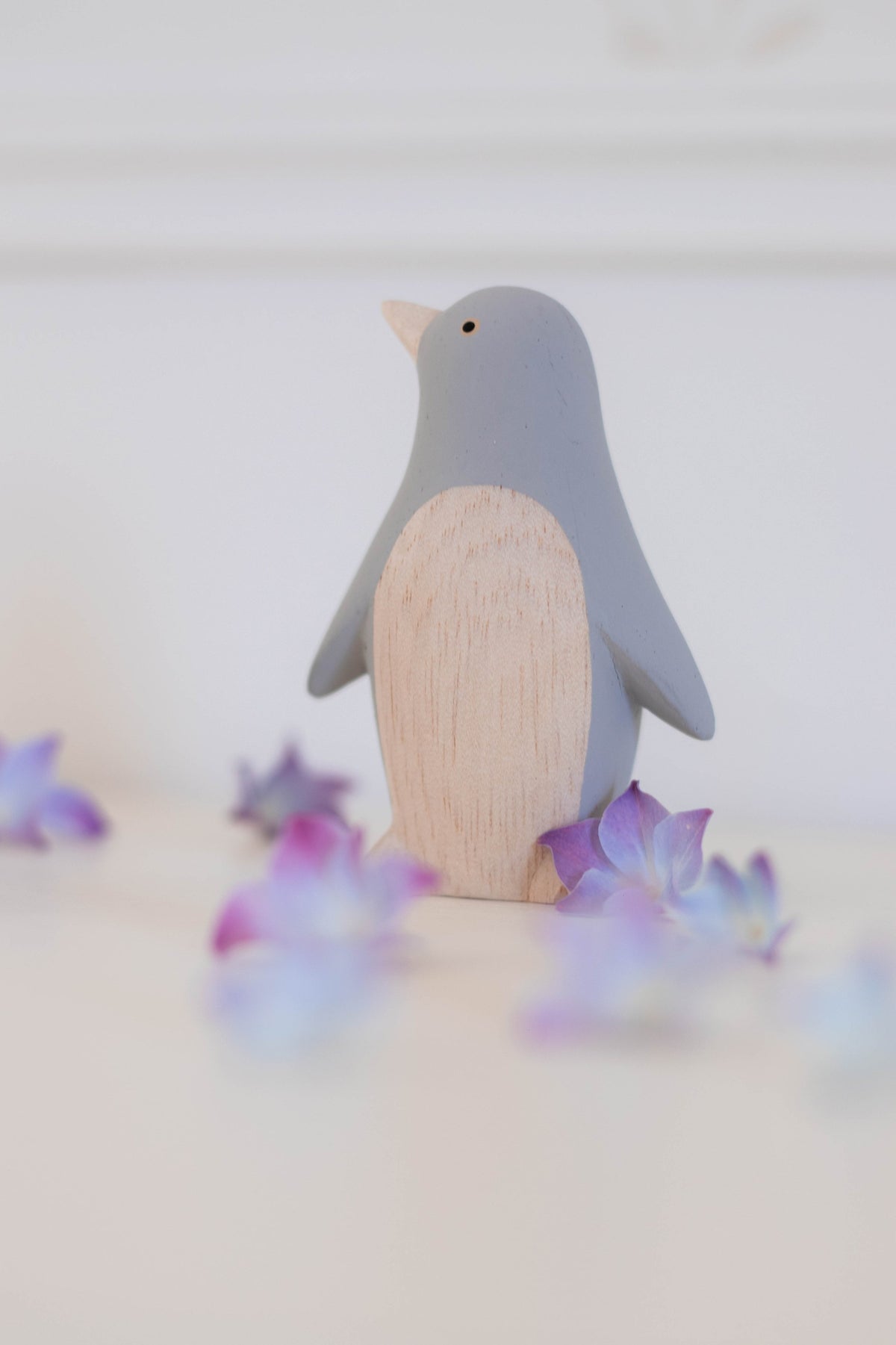 Figura de pingüino gris de madera ambientada