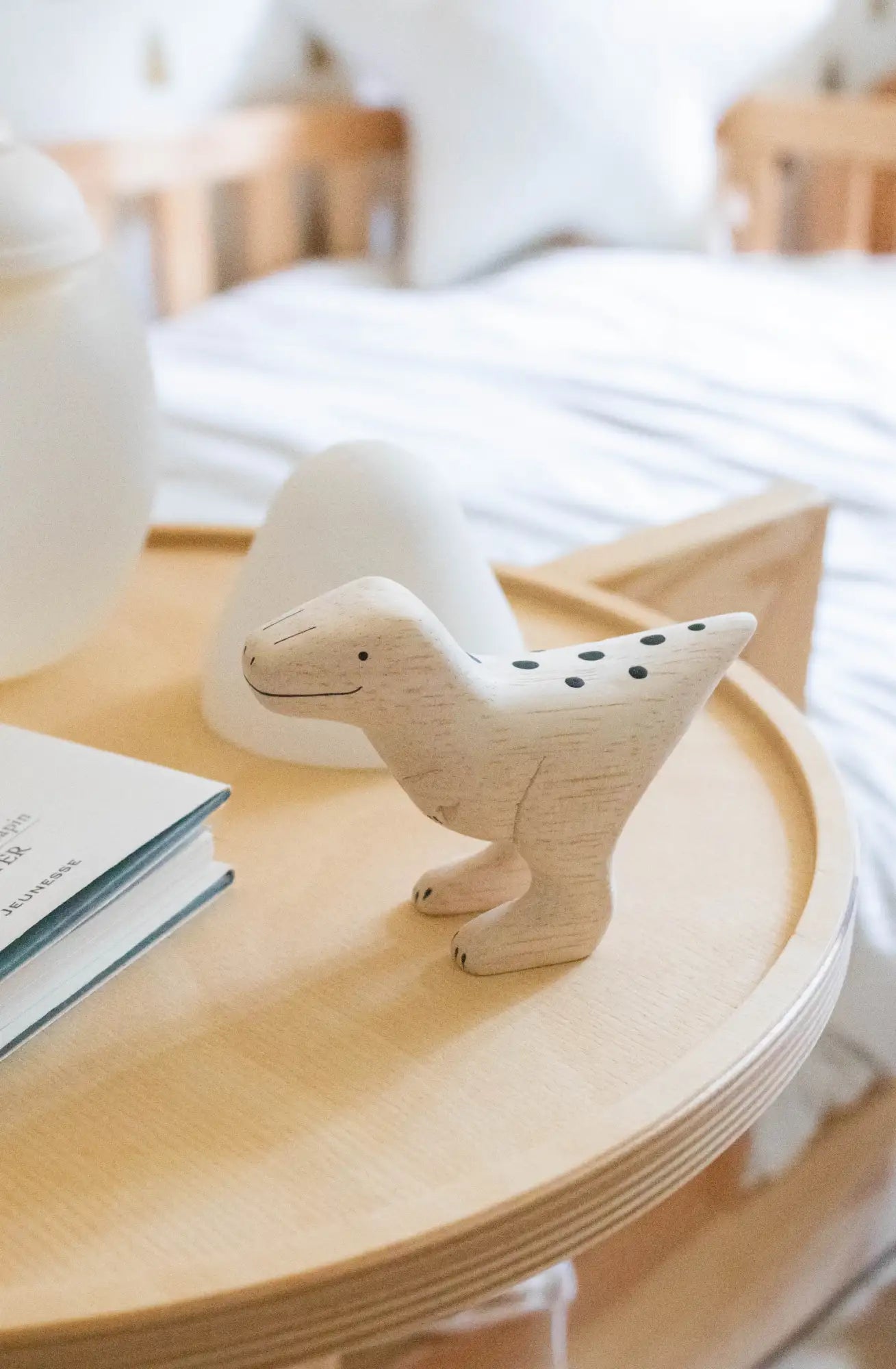 Une figurine de dinosaure en bois clair avec des marques en points noirs.